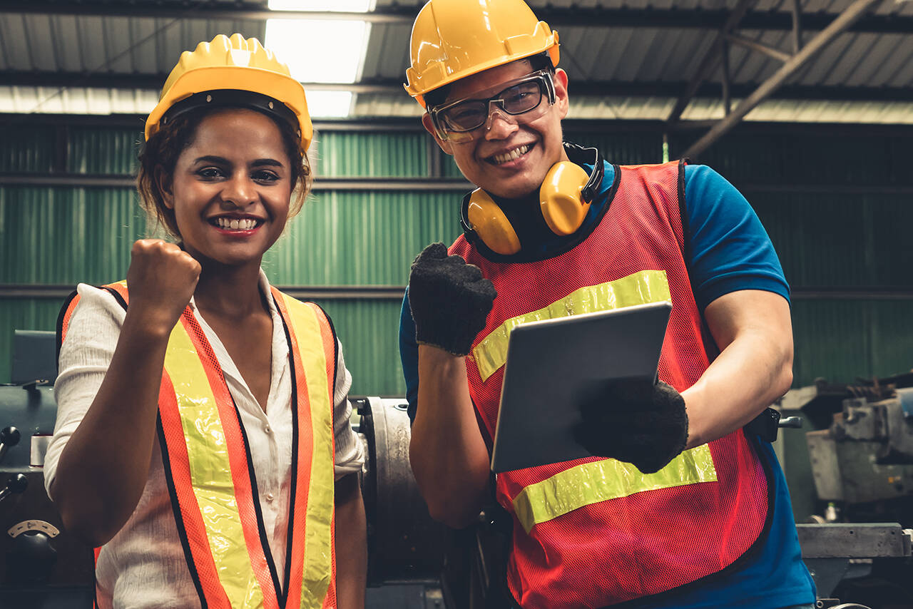 Two skillful factory engineer or worker happy portrait looking at camera . Industrial people and manufacturing labor concept .